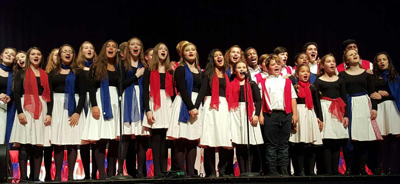 Large choir performing on stage in red, white, and blue