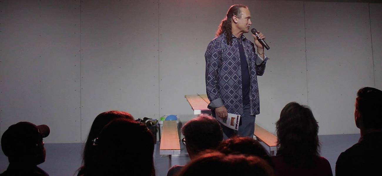 Larry Friedman speaking on stage with microphone in front of an audience